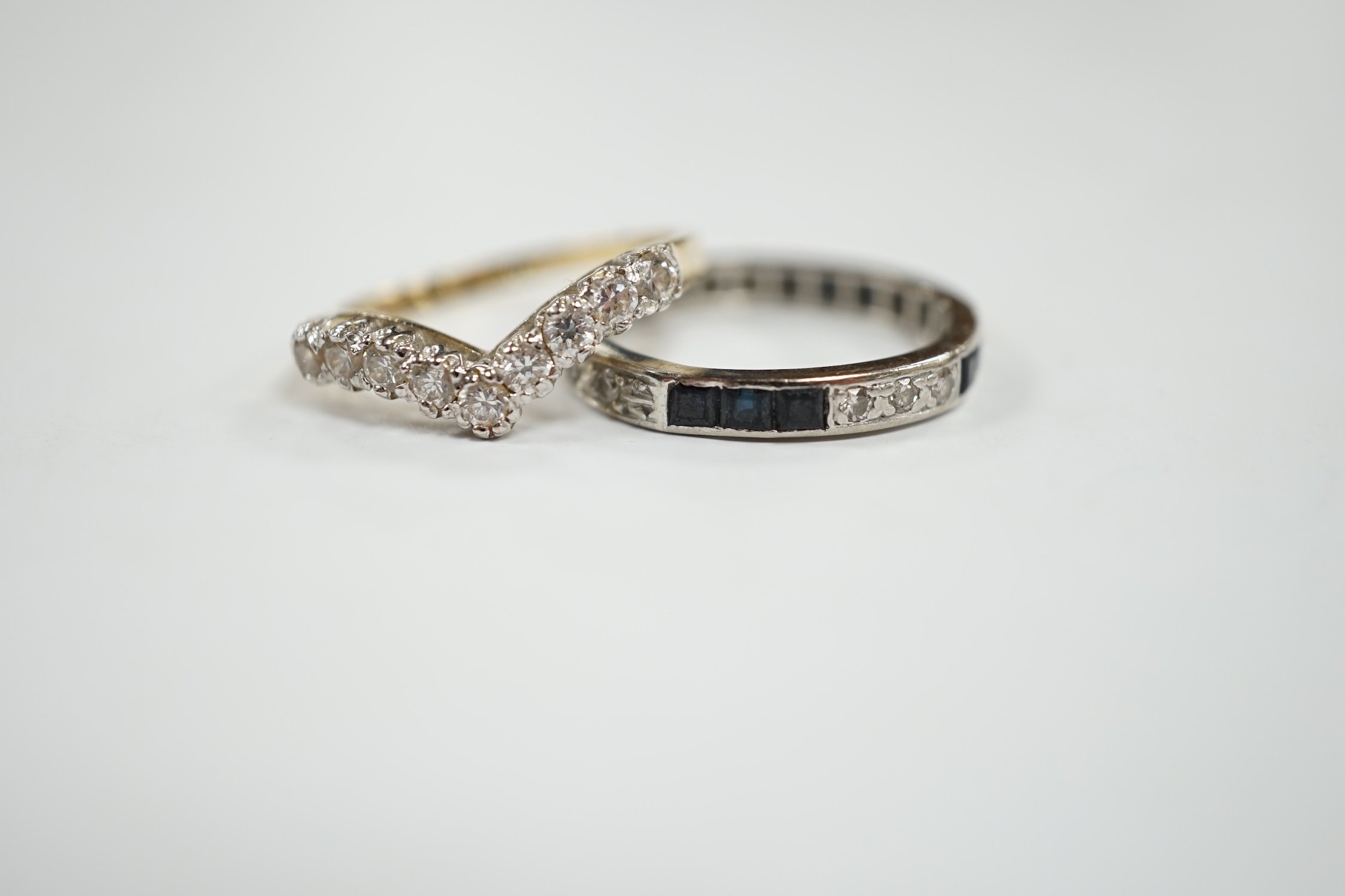 A white metal sapphire and diamond set full eternity ring, size Q/R, gross weight 3.6 grams, together with a 14k and cubic zirconia set chevron ring, gross 2.8 grams. Condition - fair to poor